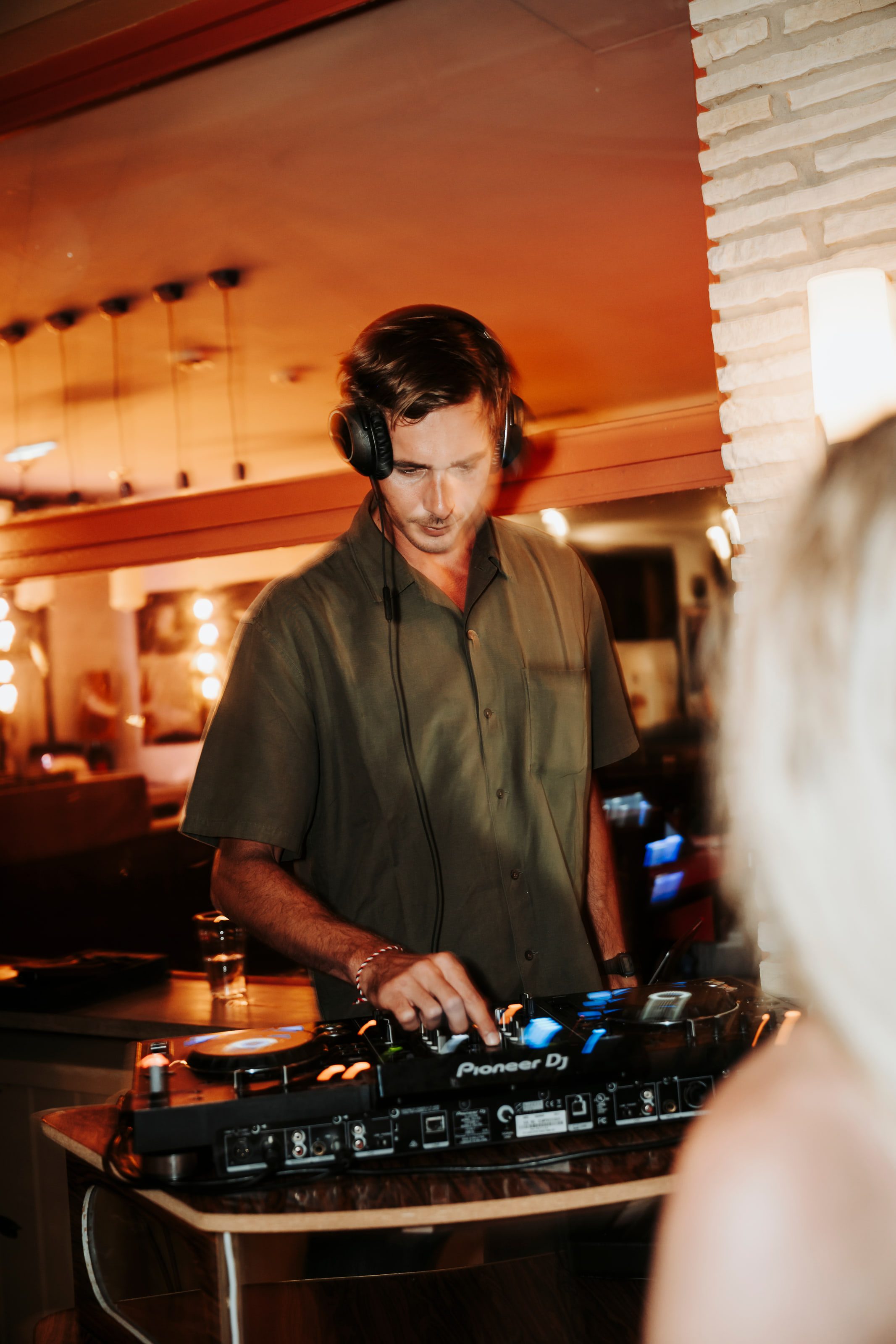 Victor Denver behind the decks in a warm, low-lit interior.